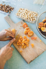 Young woman making Turkish dessert (asure) in the kitchen. Traditional Sweet Ashura, Ashura or Noah's Pudding. Woman cutting dried fruit for Ashura preparation.