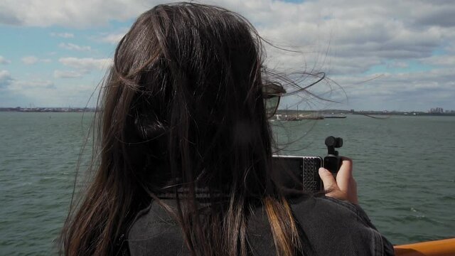 Slow Motion, Young Woman With Smartphone and Gimbal Filming New York Waterfront From Staten Island Ferry on Sunny Summer Day