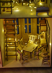 Dining room with table, chairs and a kitchen wall in an assembled house made of plywood with yellow lights conveys comfort of the hearth