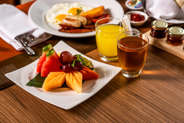A plate of fresh fruit for breakfast: grapes, watermelon, mango and fresh juices