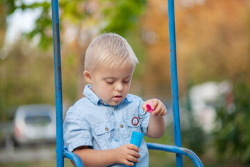 The daily life of a child with disabilities. A boy with Down syndrome blows soap bubbles....