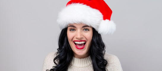 Happy woman with a Santa hat on a gray background