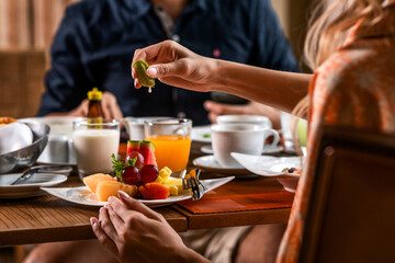 Close-up: a woman pours lime on a plate of fresh tropical fruits. Healthy breakfast