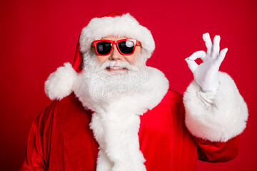 Close-up portrait of his he nice handsome cheerful cheery bearded Santa father showing ok-sign event celebratory solution advert ad isolated bright vivid shine vibrant red color background