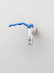 Front view of nickel faucet with blue lever handle and hose nozzle on white wall. Hardware and...