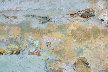 Old cracked weathered painted wall background texture. Light peeled plaster wall with falling off flakes of paint