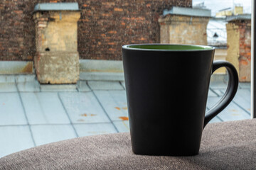 Obraz premium morning tea, coffee in cups on the background of a window and an old, brick house with a beautiful texture in a big city