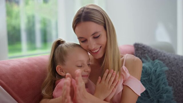 Woman and girl talking in living room. Happy mother and daughter clapping hands