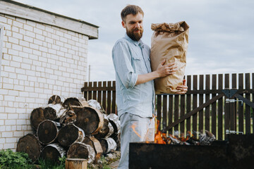 A man with a craft bag of charcoal in his hands. High quality photo
