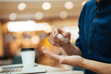 close up. the man sprays antiseptic on his hands.