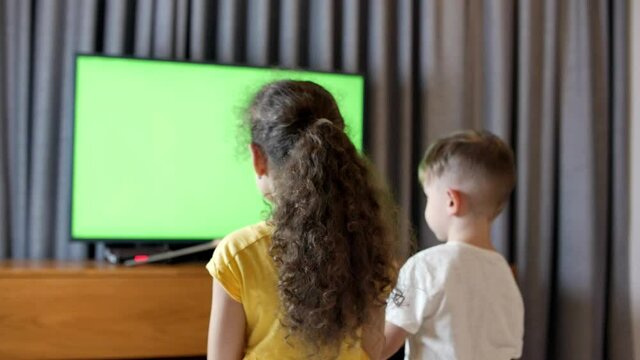 Portrait ute Little Kids While Watching TV on Laptop. Boy and Girl Watch Cartoon on Laptop on Living Room. Concept Video Game, Entertainment, Emotions, Family. Children Brother and Sister Watching TV