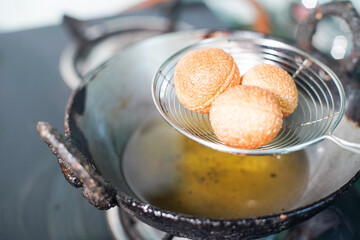 shot of north indian street food snack gol gappe pani puri or puchke being fried from dough in hot oil to make them round hollow golden ball spheres - obrazy, fototapety, plakaty