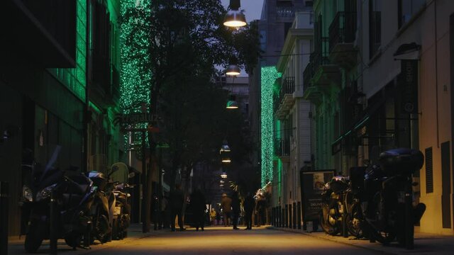 People talking on quiet street at dusk, green christmas lights wide shot