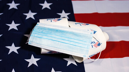 Face mask on stack of I Voted stickers for American elections on Usa flag.