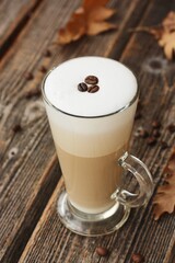 Coffee latte with beans and oak leaves on the table