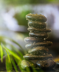 Zen stones with water drops stacked on abstract background.