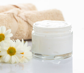 Fototapeta na wymiar Moisturizing cream in glass jar and chamomile on white background.