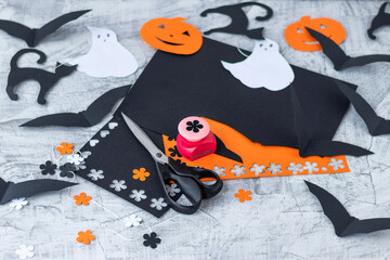 Preparation for Halloween Decoration for the holidays, cutting from colored paper on a white brick wall. orange and black colored paper, scissors, pencils, figured hole punch