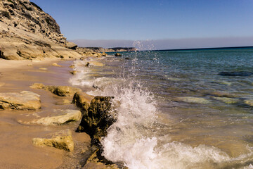 The waves hit rock on portuguese beach and splashes into drops of water