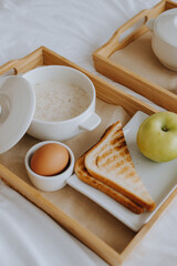 Fototapeta na wymiar Breakfast in the hotel. Porridge, boiled egg, toast, coffee, porridge with berries on a tray. High quality photo