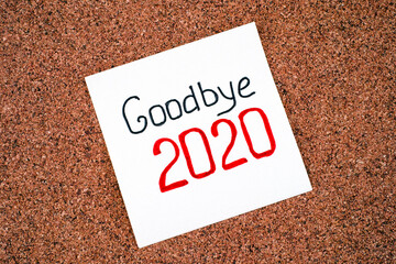 Paper note with words Goodbye 2020 on cork background.