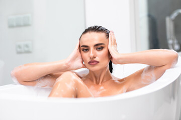 Obraz na płótnie Canvas Close up hot woman lying in foam at bathroom. Sexy woman relaxing at luxury bathtub.