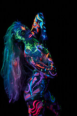 Art woman body art on the body dancing in ultraviolet light. Bright abstract drawings on the woman body neon color. Colored hair and face