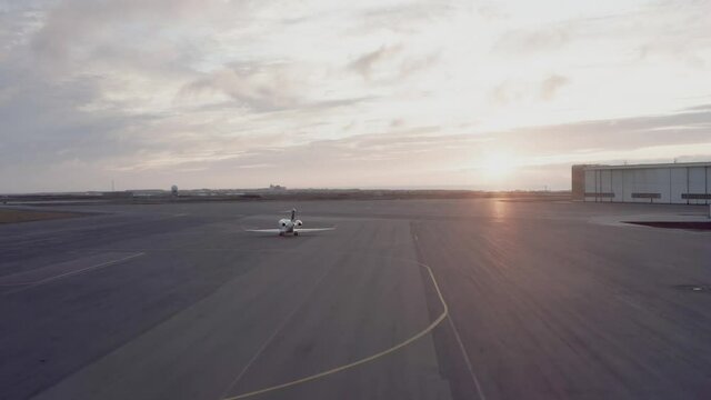 Business jet departing on open tarmac of airport at dusk, taxiing towards runway