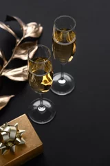 Foto op Aluminium Two glasses of champagne over black background and golden Christmas decoration. Holiday decorations on dark table. © svetlana_nsk