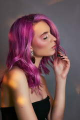 Naklejka premium Portrait of a woman with bright colored flying hair, all shades of purple. Hair coloring, beautiful lips and makeup. Hair fluttering in the wind. Sexy woman with short hair. Professional coloring