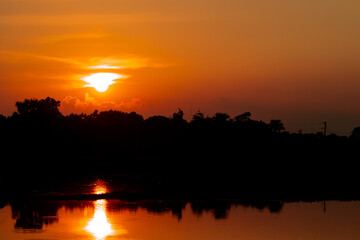 Obraz premium A beautiful golden sunset over the lake in the village