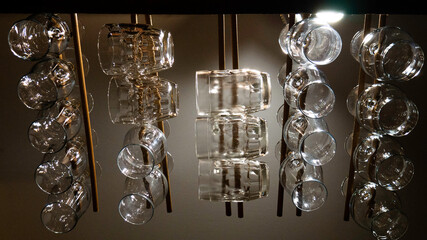 Glass pint beer mugs handing from the wood ceiling of a bar. Different types of mugs for different beers.