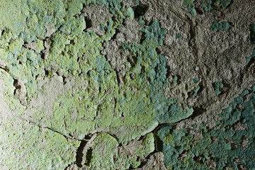 Old stone wall with peeling yellow and blue paint close-up, damaged texture