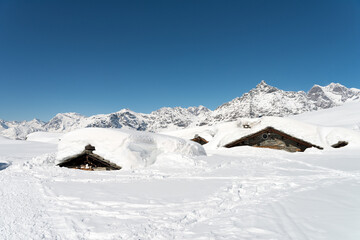 Fototapeta na wymiar Valmalenco, Lombardy Alps, Italy: Mountain huts submerged by snow