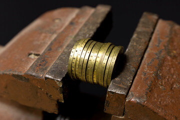A few coins in a metal vise. Concept of economic problems. Selective focus.