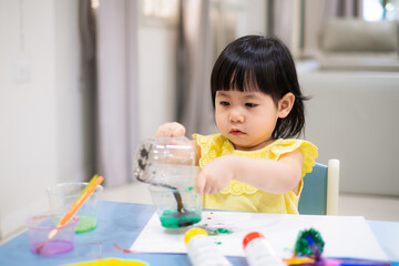 child painting with a paintbrush on the table. toddler draw watercolor. - 384820817