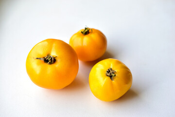 Three yellow tomatoes on a white background