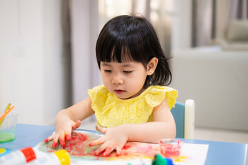 Asian toddler girl paint watercolor by her hand.
