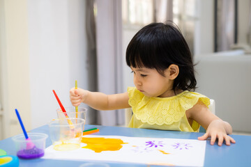 child painting with a paintbrush on the table. toddler draw watercolor. - 384821014
