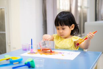 child painting with a paintbrush on the table. toddler draw watercolor. - 384821024