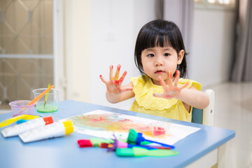 the toddler is happy with the painted colorful hands. baby girl smile with painted colorful hand. - 384821212