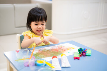happy Toddler painting water color with her hand. smiley baby girl with painted hand. - 384821225
