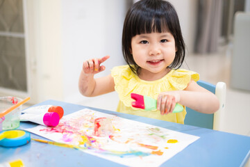 the toddler is happy with the painted colorful hands. baby girl smile with painted colorful hand. - 384821258