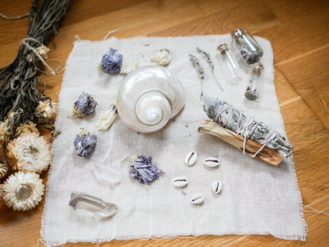 Witch altar to perform rituals with shells, dried flowers, bundle of sage and crystals