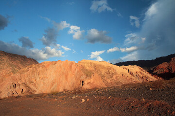 Beautiful view of the arid desert, sand and rocky formation shining and reflecting the sunset light on its surface. 