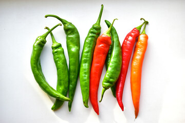 Green and red capsicum fruits on a white background