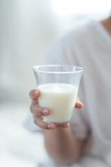 woman in white hand hold milk glass for early morning.