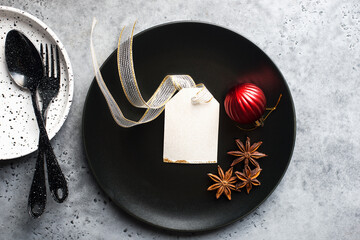 Christmas table set minimalism style in black and red on a plain gray background with black cutlery. Top view.,