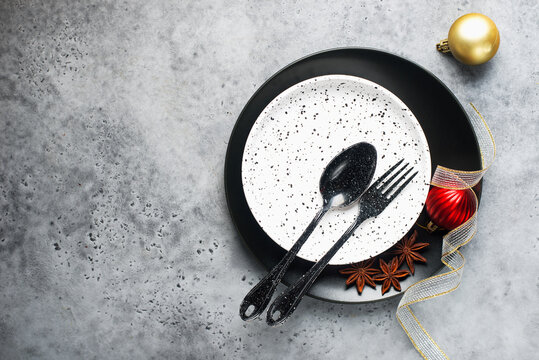 Christmas table set minimalism style in black and red on a plain gray background with black cutlery. Top view.,