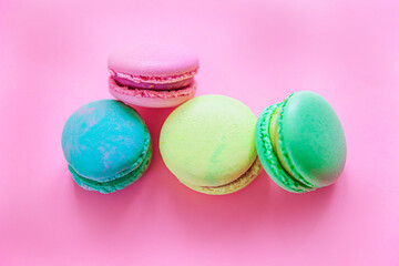 Fototapeta na wymiar Sweet almond colorful pink blue yellow green macaron or macaroon dessert cake isolated on trendy pink pastel background. French sweet cookie. Minimal food bakery concept. Flat lay top view, copy space